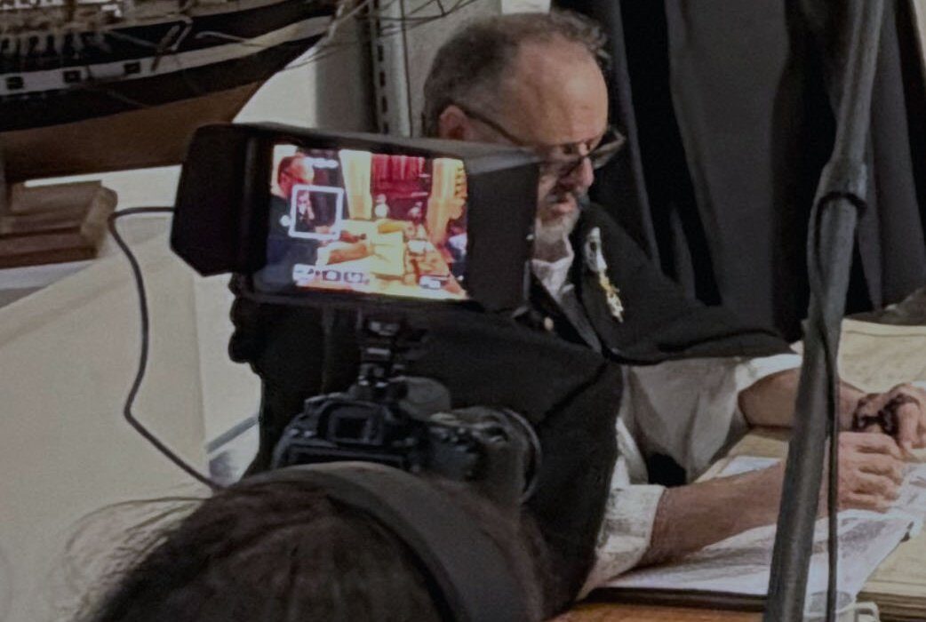 Une élève cadre au moniteur de la caméra pendant qu'un comédien joue à une table, une perche de son traverse le cadre
